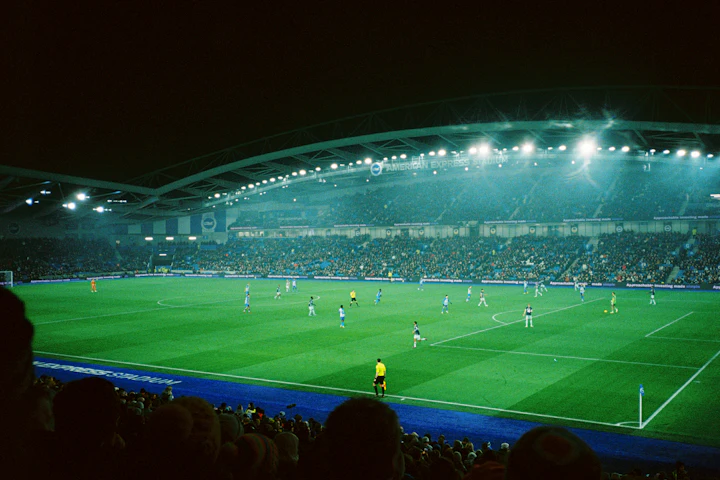 Partido de fútbol en un estadio iluminado de noche