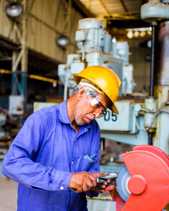 Operario con casco trabajando en una amoladora industrial